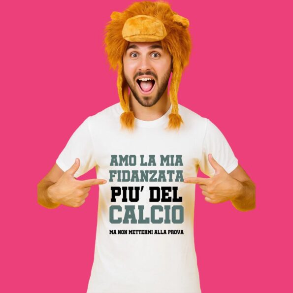 ragazzo felicissimo con cappello da leone che indica la sua maglietta con scritto "amo la mia fidanzata più del calcio, ma non mettermi alla prova"